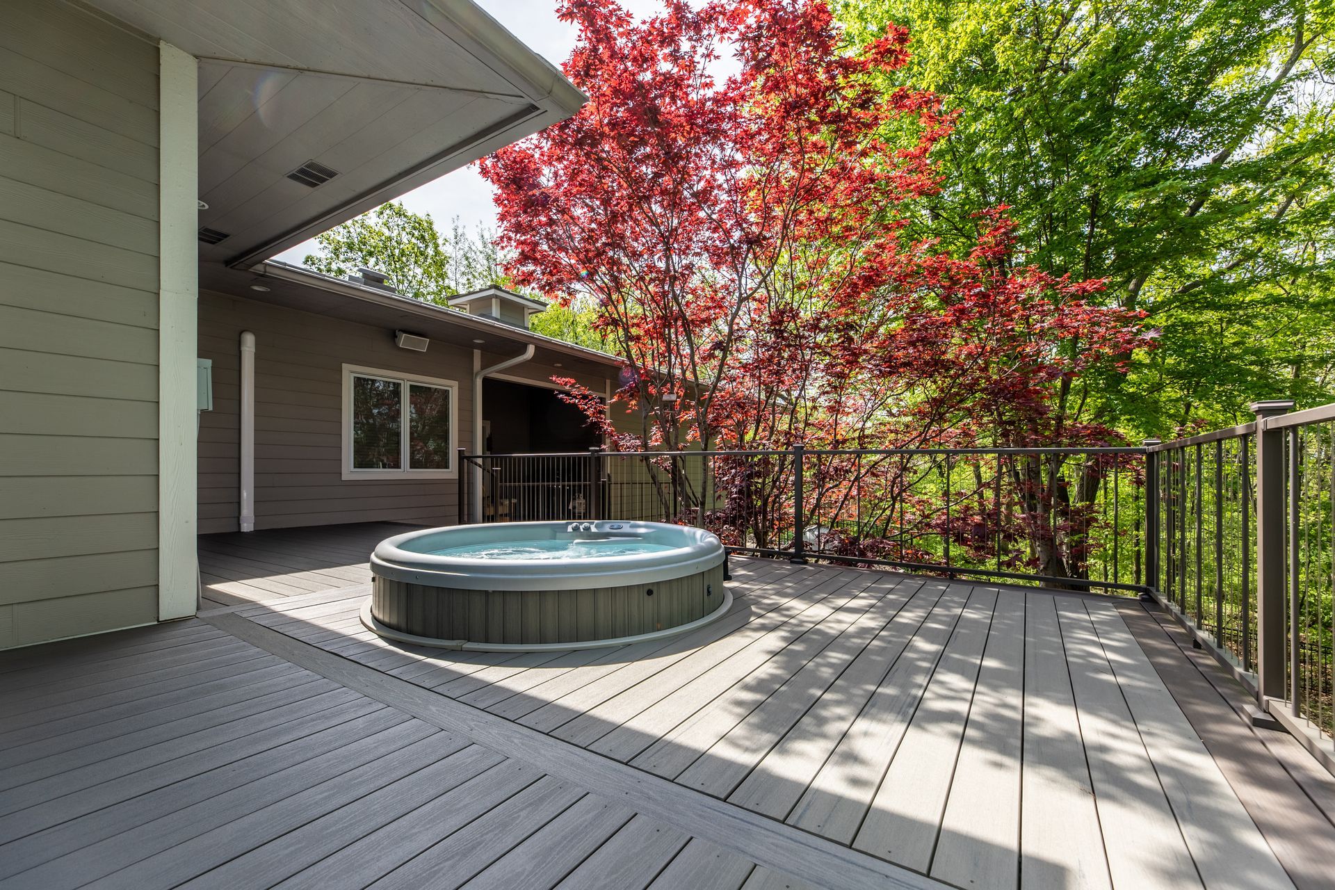 There is a hot tub on the deck of a house.