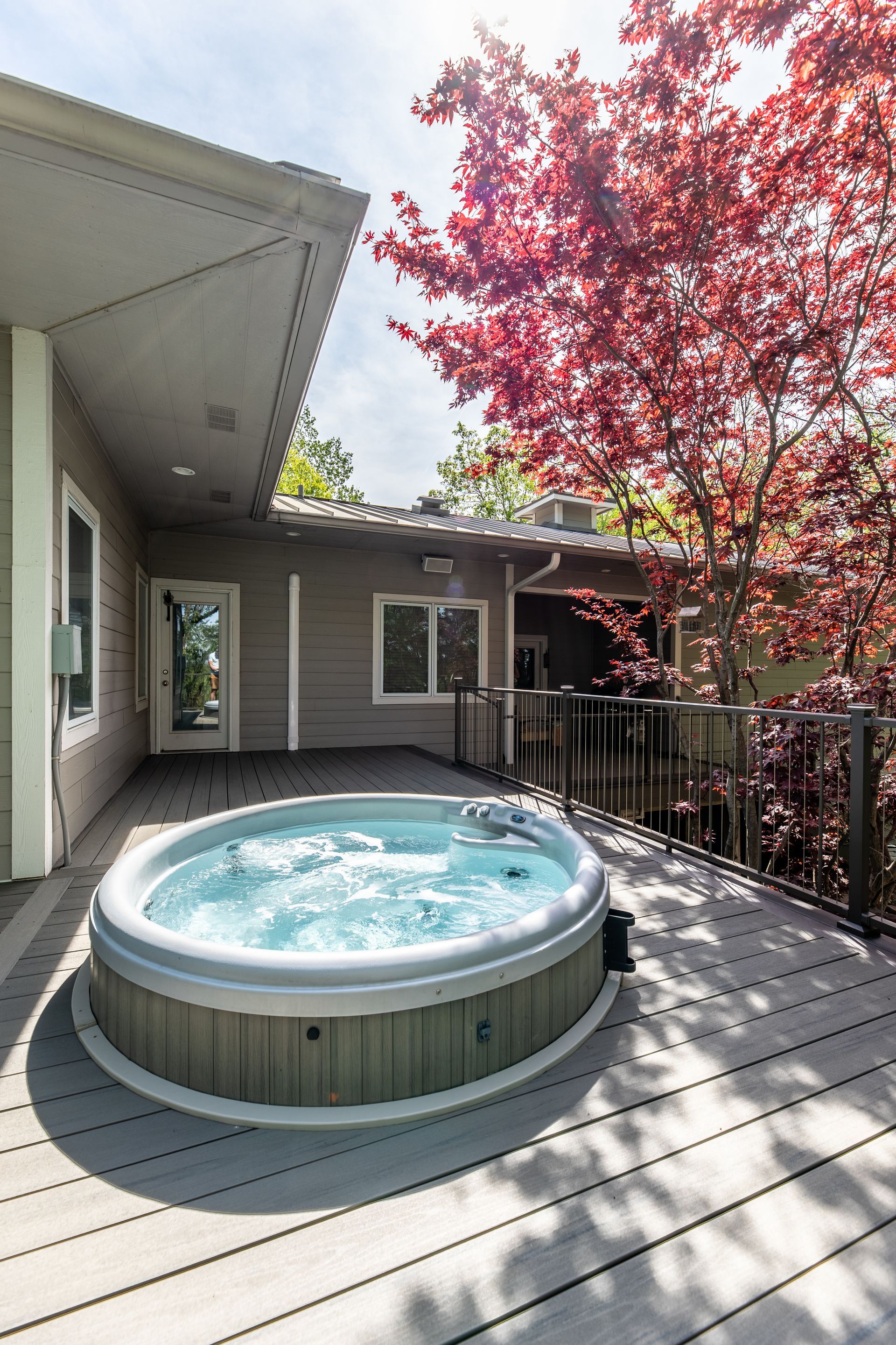 There is a hot tub on the deck of a house.
