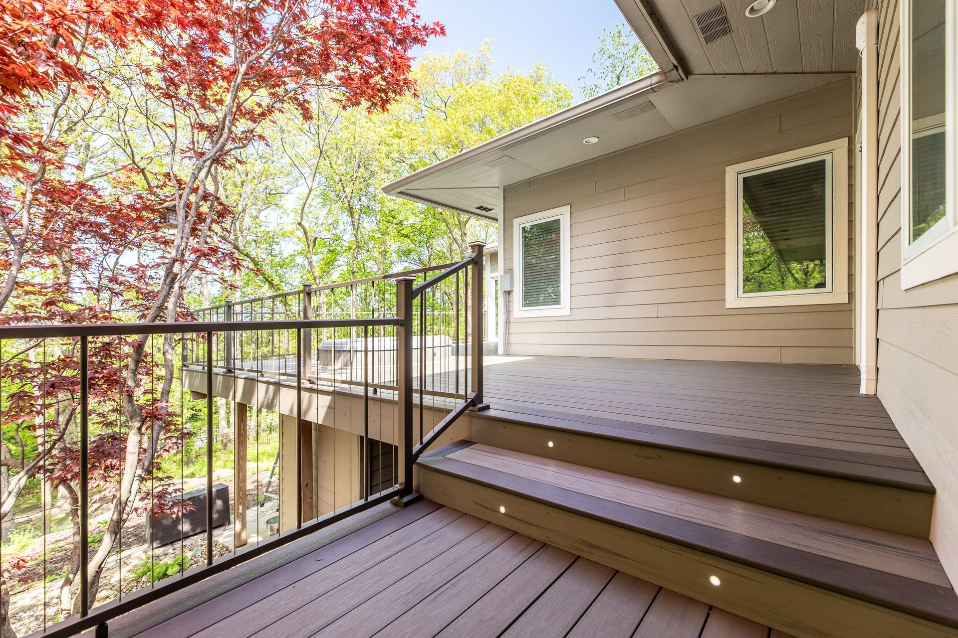 There is a deck with stairs leading up to it in front of a house.