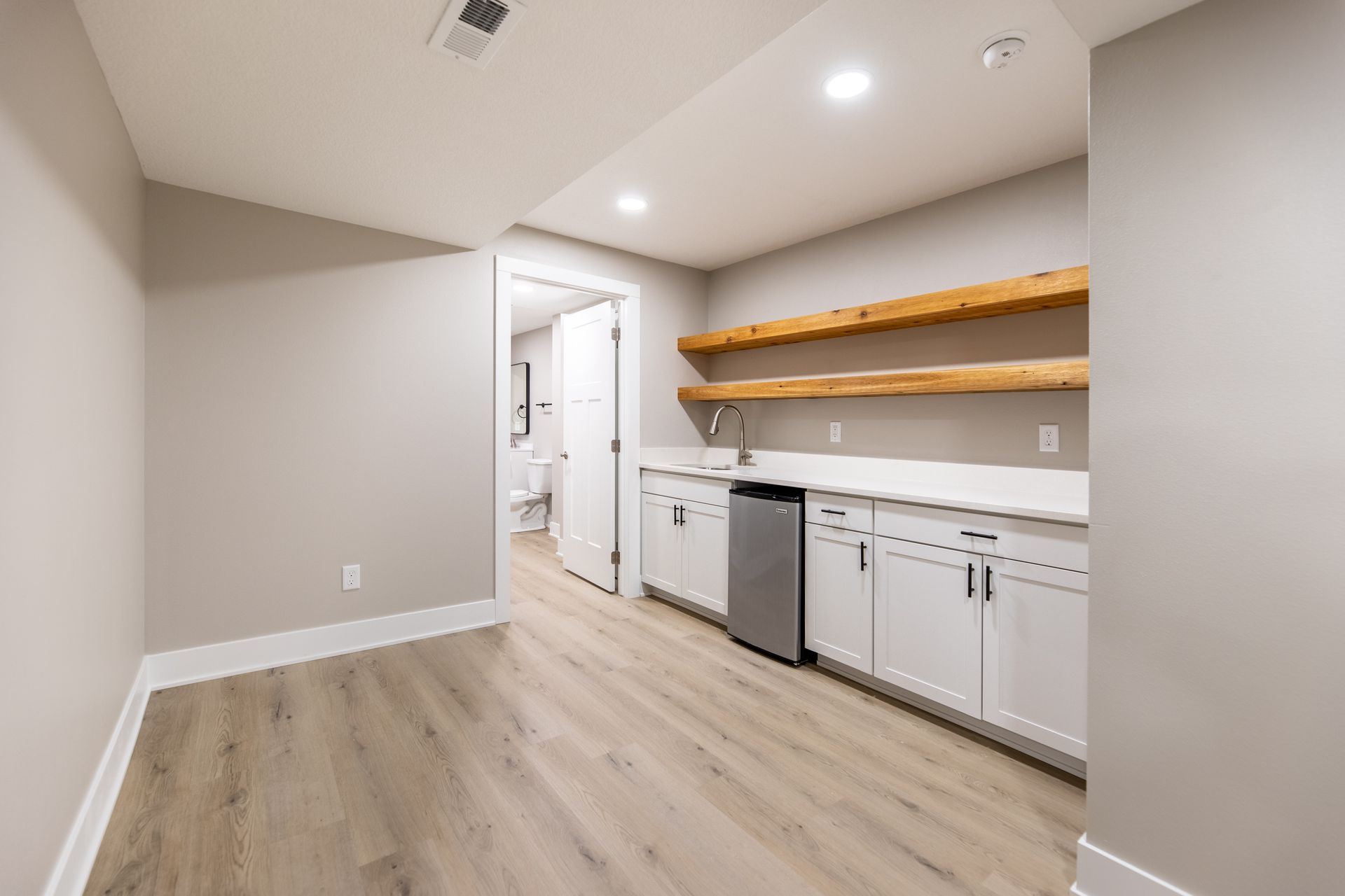 An empty room with hardwood floors and white cabinets.