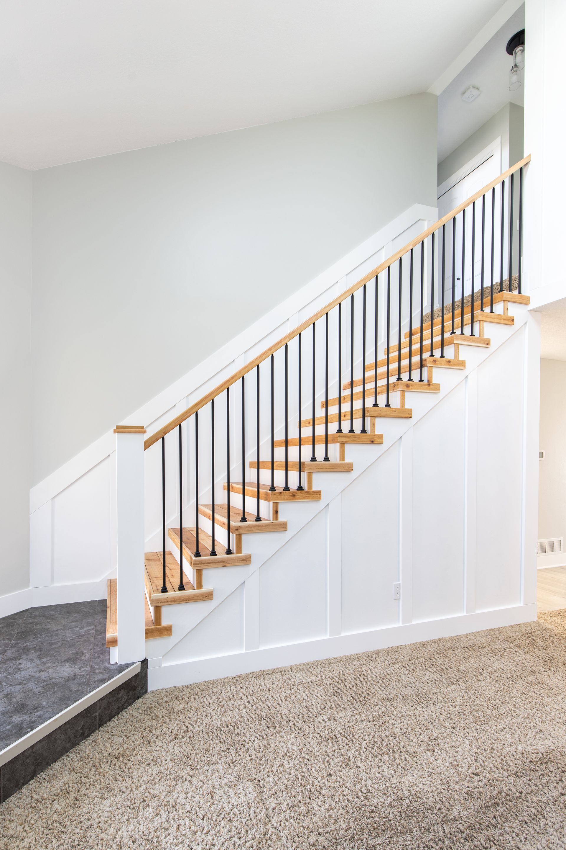 A staircase with wooden steps and a black railing in a living room.