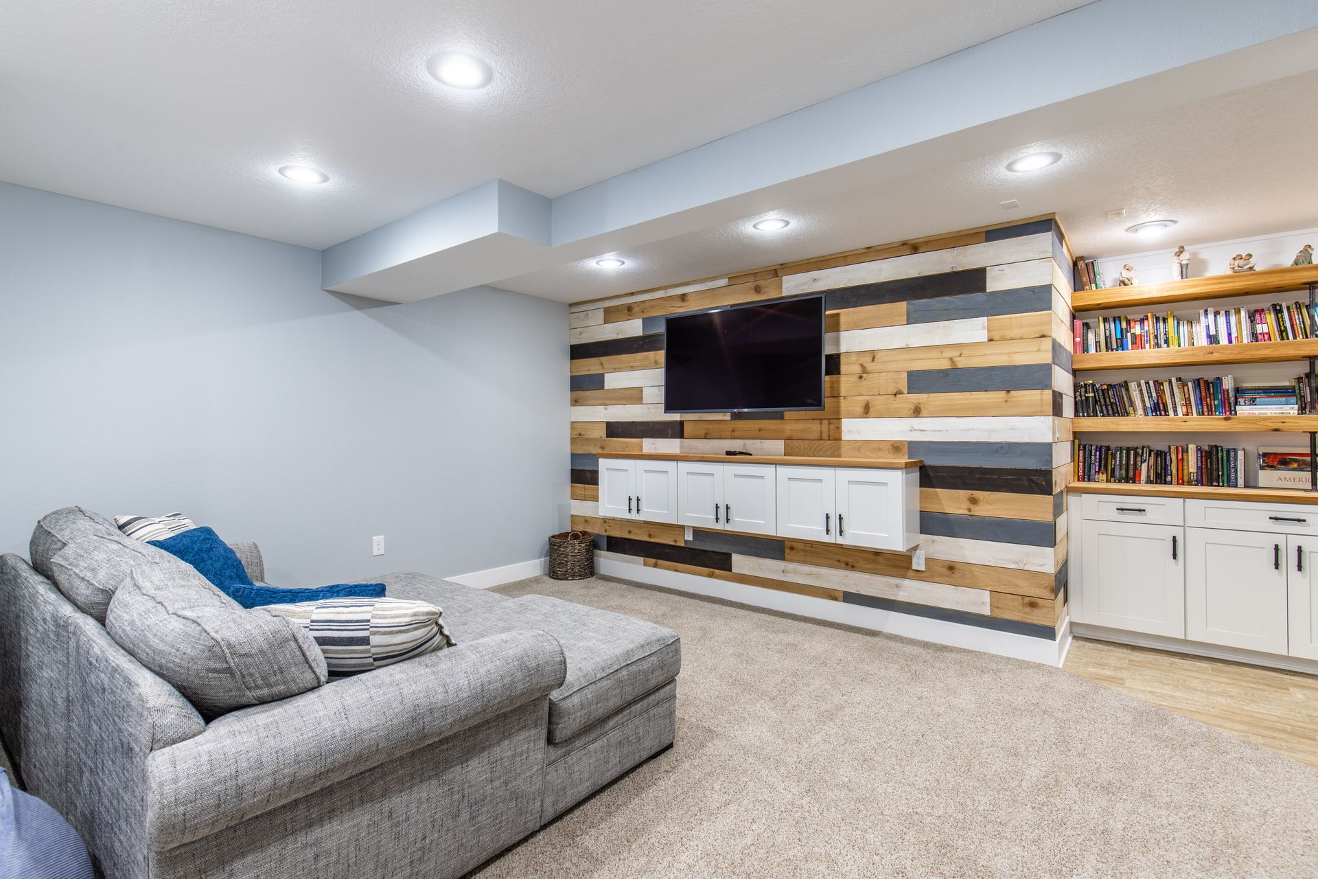 A living room in a basement with a couch and a flat screen tv.