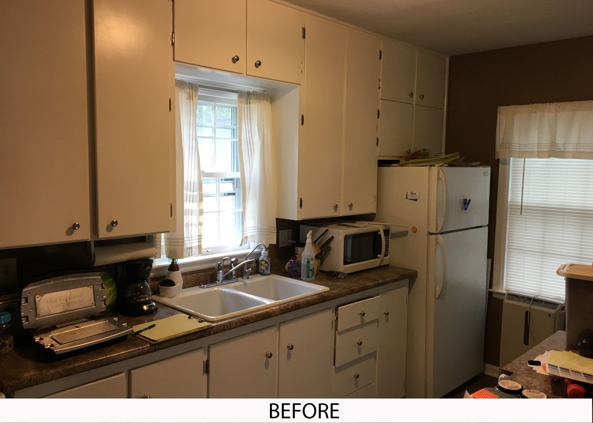 A before picture of a kitchen with white cabinets and a refrigerator.