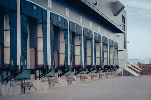 Loading docks on a warehouse building. Blue awnings over bay doors, concrete platform.