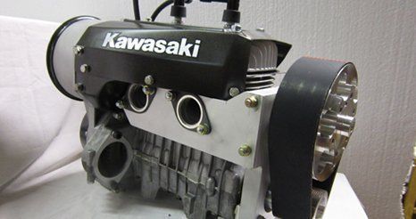 Kawasaki engine, black and silver, with belt drive and spark plugs visible.