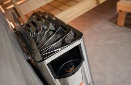 Close-up of a metal container holding black kitchen utensils on a countertop