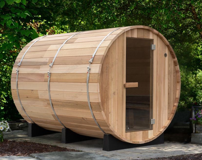 Wooden barrel-shaped sauna with an open front door and black support feet