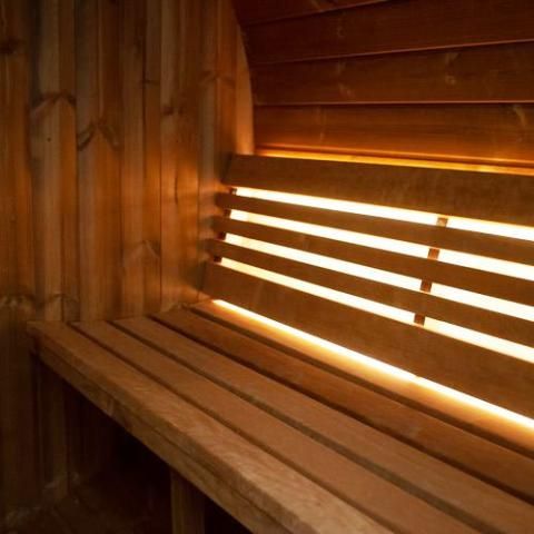 Wooden sauna interior with bench seating and warm light filtering through slatted wall
