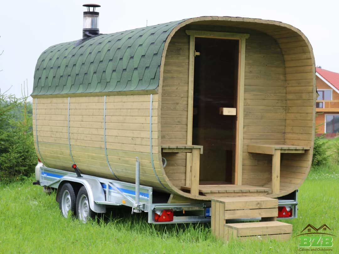 Small wooden caravan on a trailer, with a green curved roof and front steps.