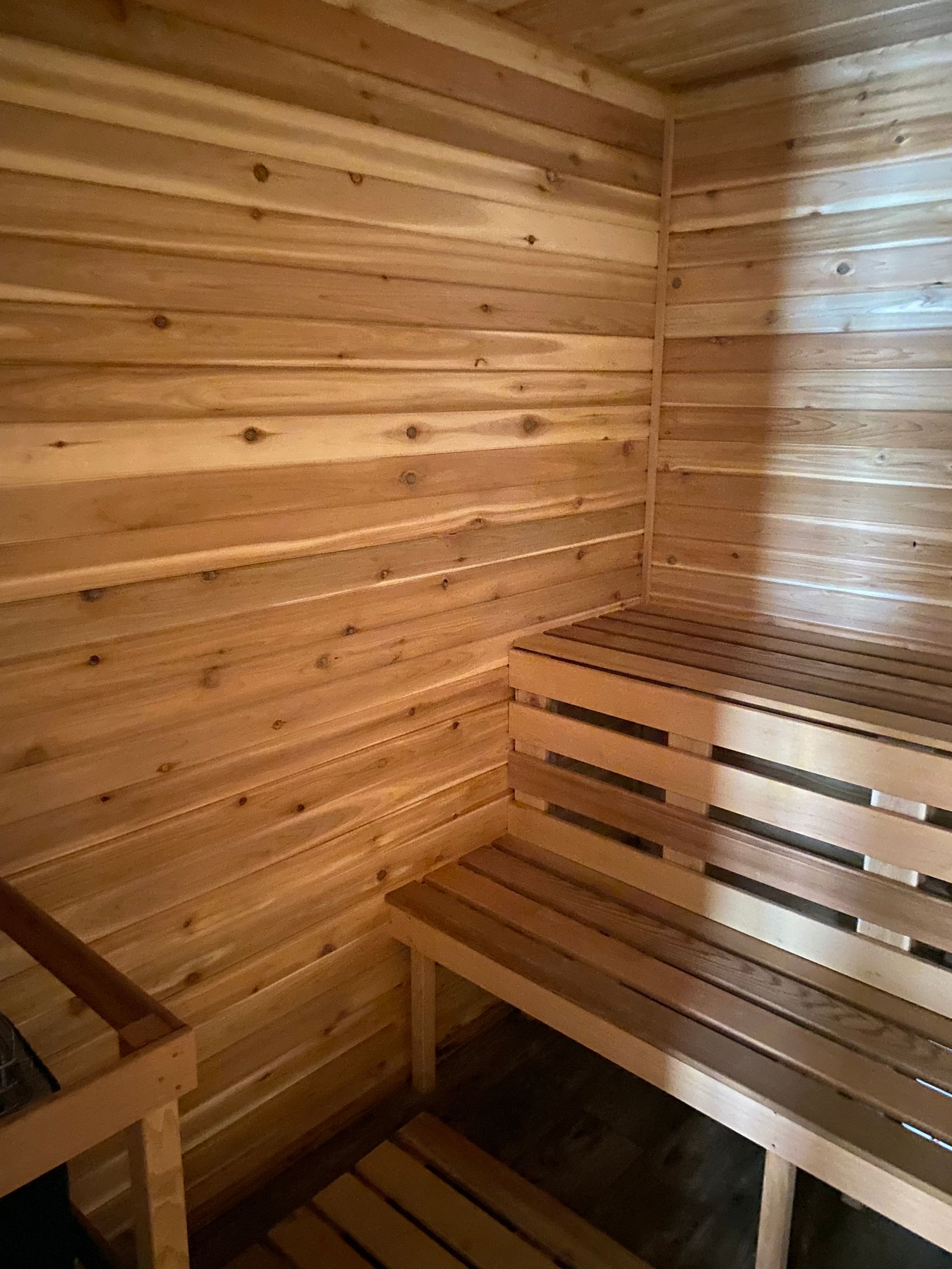 Wood-paneled sauna interior with wooden benches and warm lighting