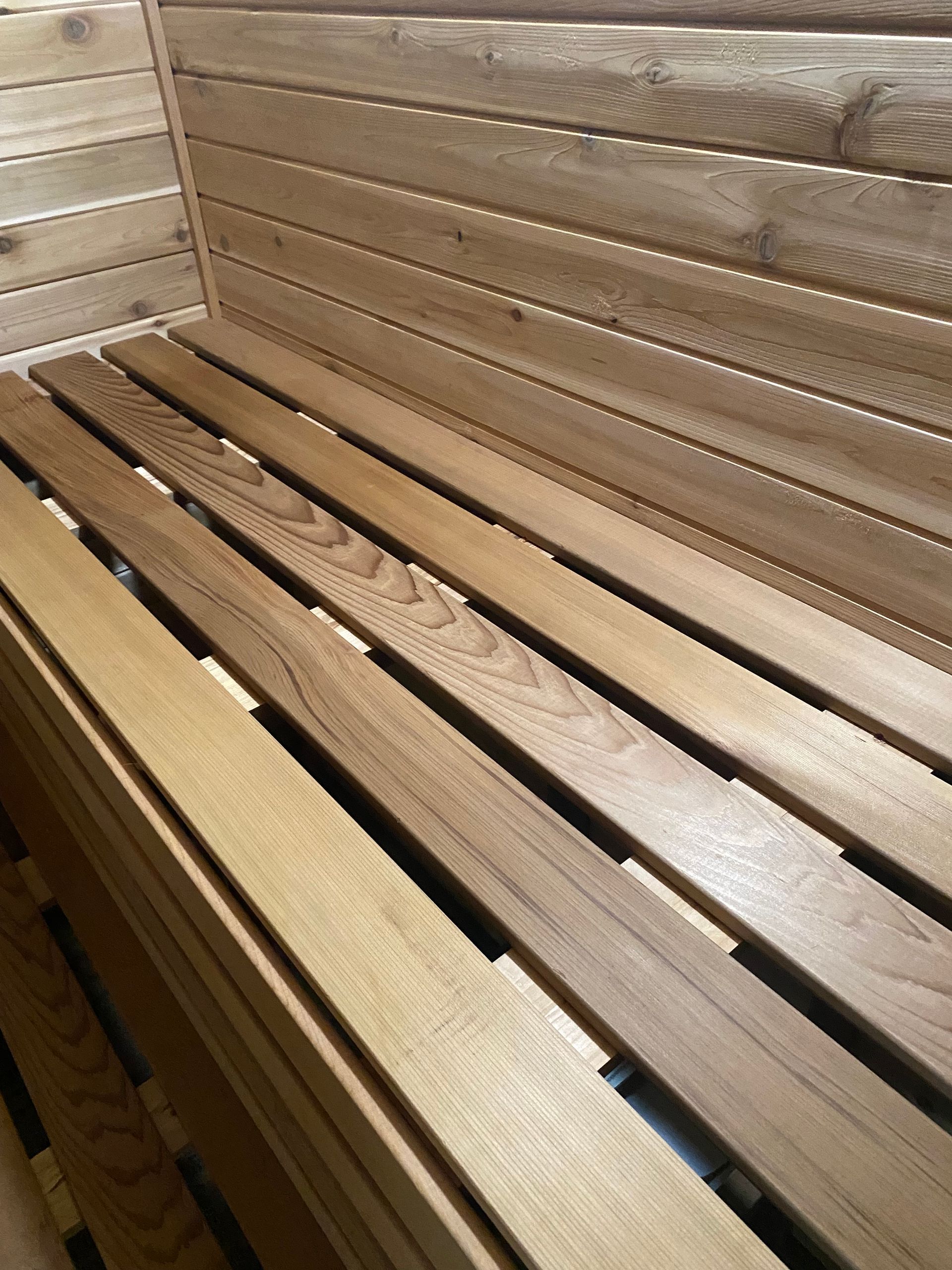 Wooden sauna bench and slatted wall in a warm, light-colored interior.