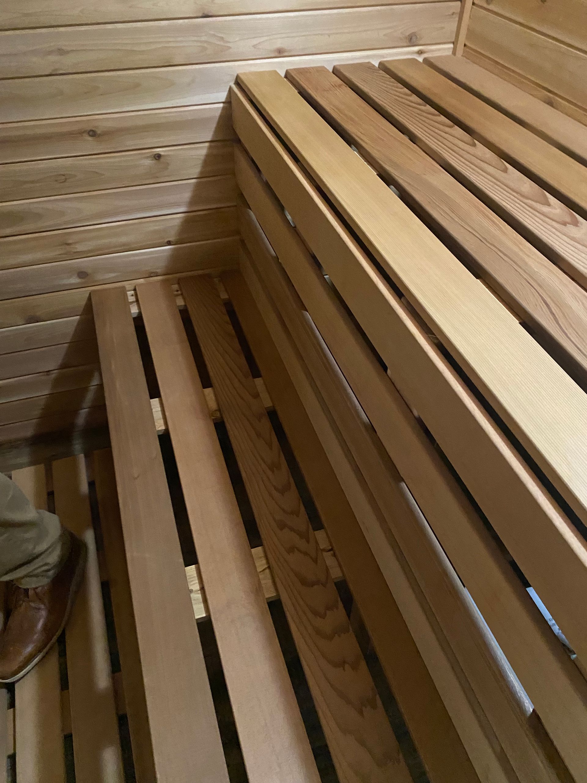 Wooden sauna bench and step with slatted seats against a wood-paneled wall