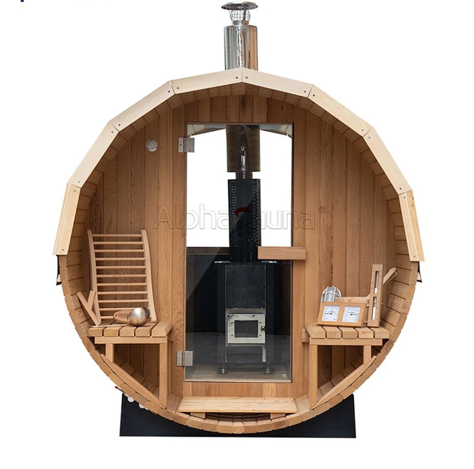 Round wooden sauna interior with benches, heater, and a small stove centered inside a barrel-shaped room