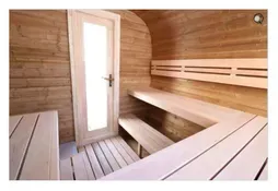 Wood-paneled sauna with benches, a glass door, and warm lighting