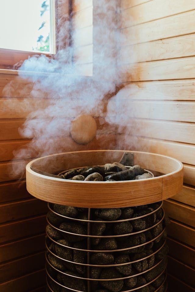 Wooden barrel sauna stove releasing steam in a cedar-paneled room