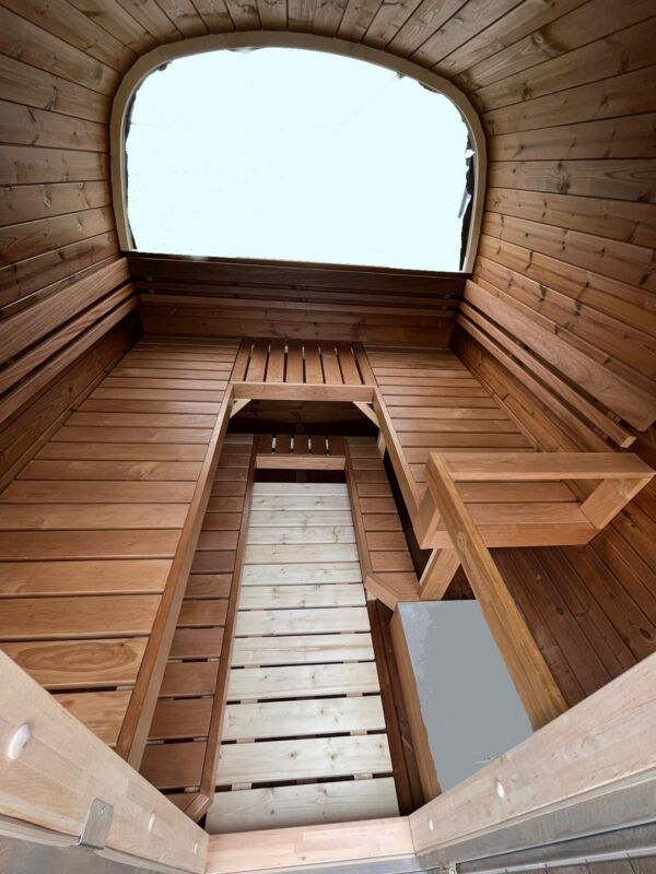 Looking up inside a wooden sauna with benches and a skylight.