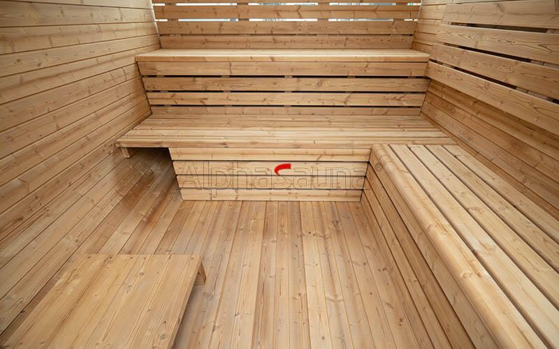 Wooden sauna interior with benches along the walls and a central heater on the floor