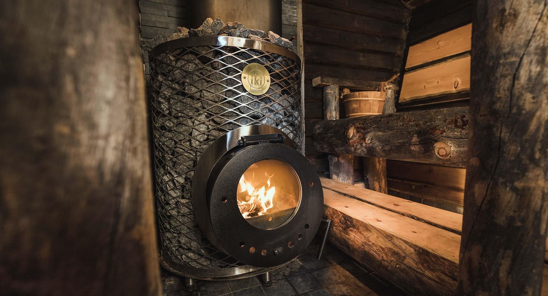 Black vintage stove or furnace glowing in a rustic wood-paneled interior
