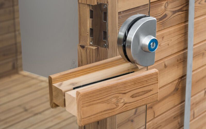 Wooden sliding door latch with a silver lock on a rail track