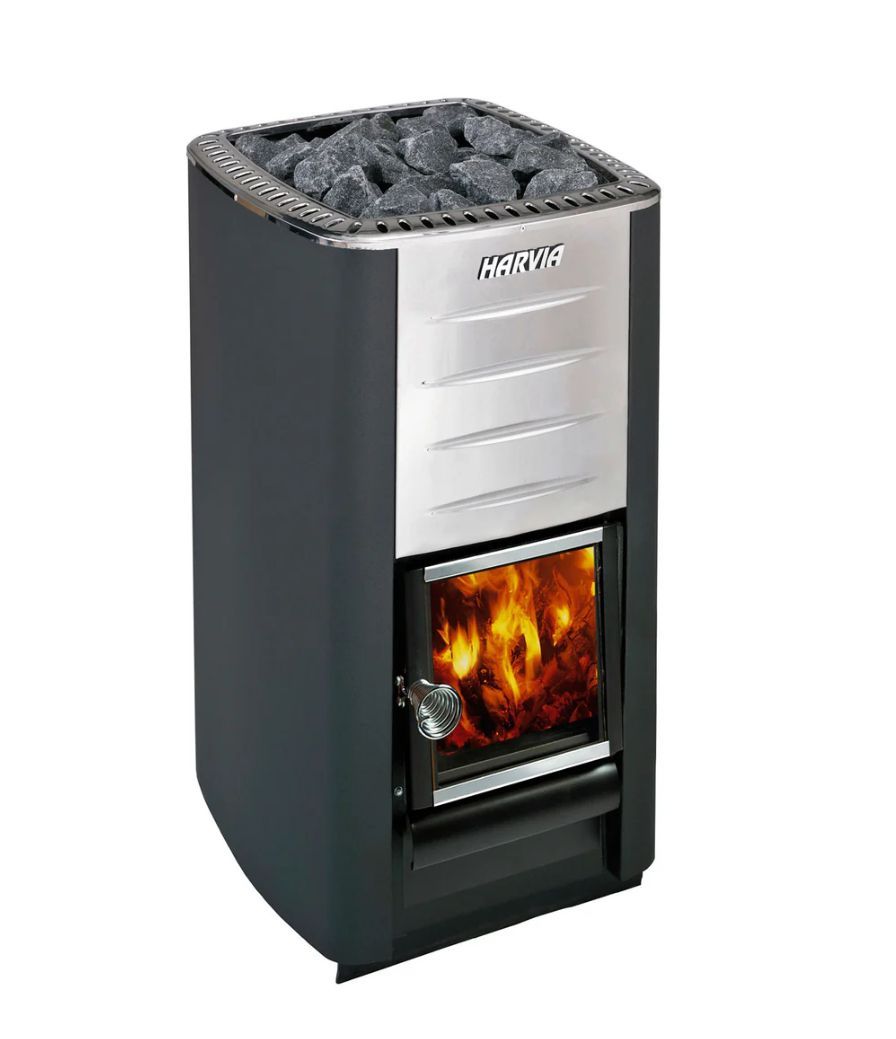 Tall black sauna stove with silver front, rocks on top, and a glowing fire behind glass door