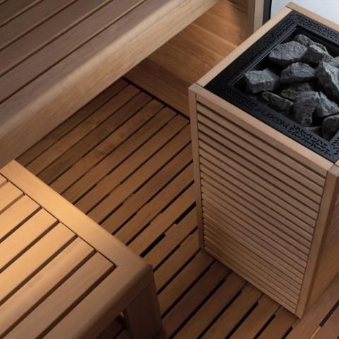 Wooden sauna bench and floor with a heater filled with rocks