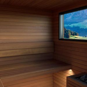 Wood-paneled sauna interior with a window overlooking a green mountain valley.