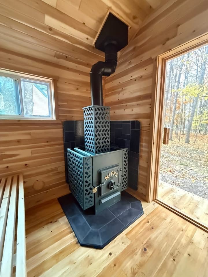 Black metal wood-burning stove with open front door and decorative side panels
