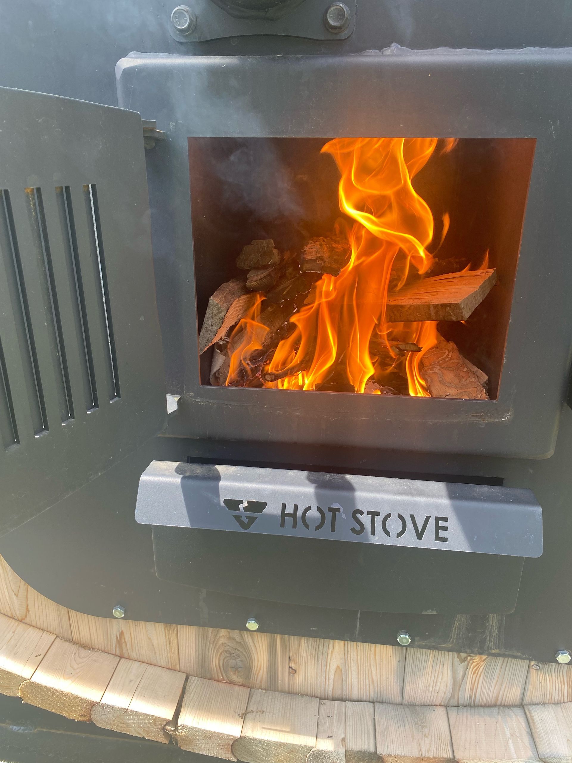 Small black wood stove with a fire burning inside, viewed through the open front door.