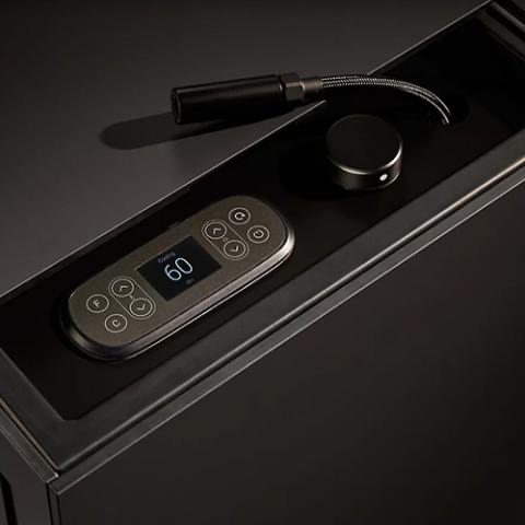 Black control panel with lit buttons and a 60 display, next to a cable and round knob on a dark device.