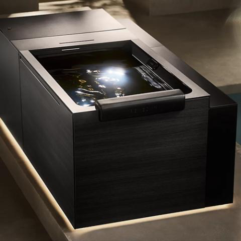 Black rectangular electronic display or touchscreen embedded in a sleek dark device, glowing in a dim room