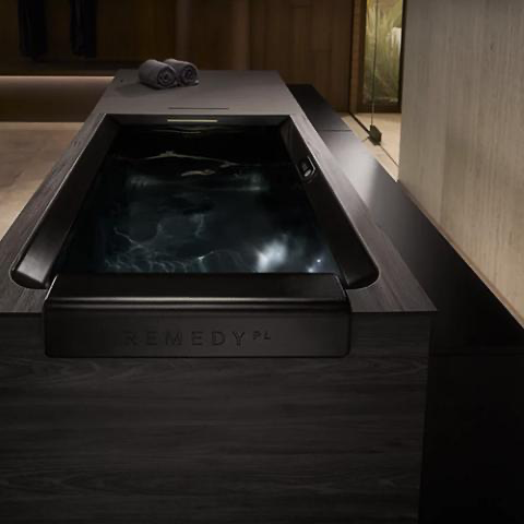 Dark wood rectangular bathtub with a black interior and built-in deck.