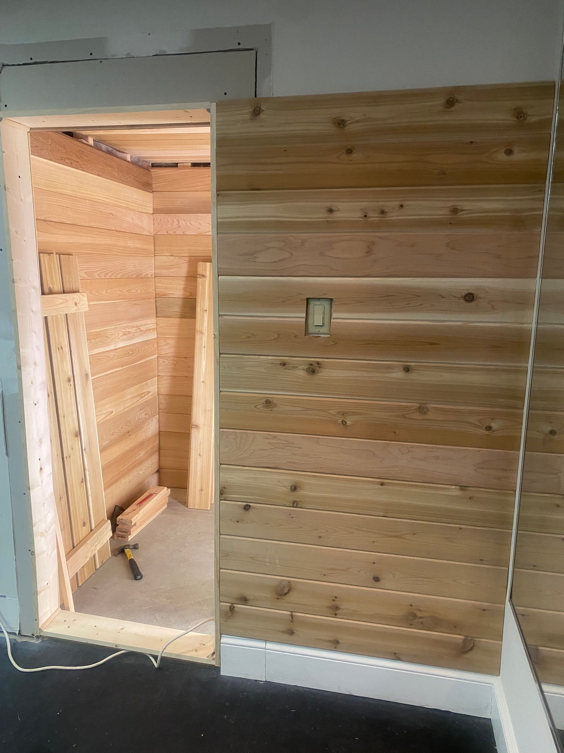 Partially finished interior doorway with exposed wood wall and a light switch panel.