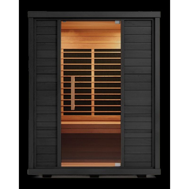 Black outdoor sauna on a wooden deck beside lounge chairs, with autumn trees beyond the glass wall.