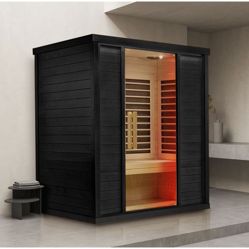 Black indoor sauna with open glass doors and warm orange lighting in a modern room infrared cabin