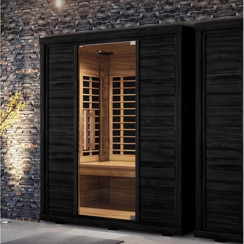 Modern black wood sauna exterior with a warmly lit interior and stone wall backdrop infrared sauna