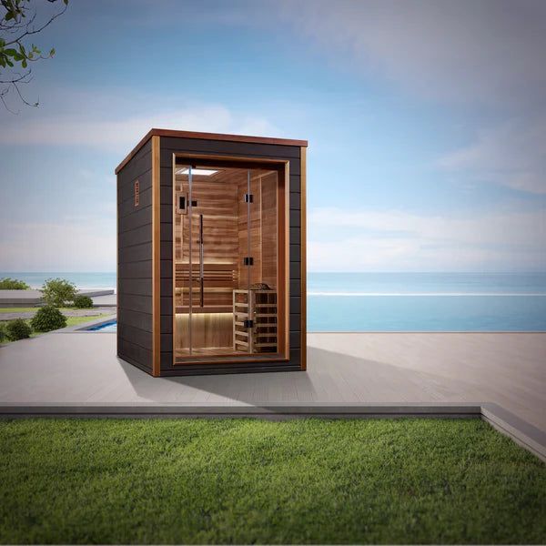 Modern wooden sauna cabin on a patio overlooking the sea at sunset
