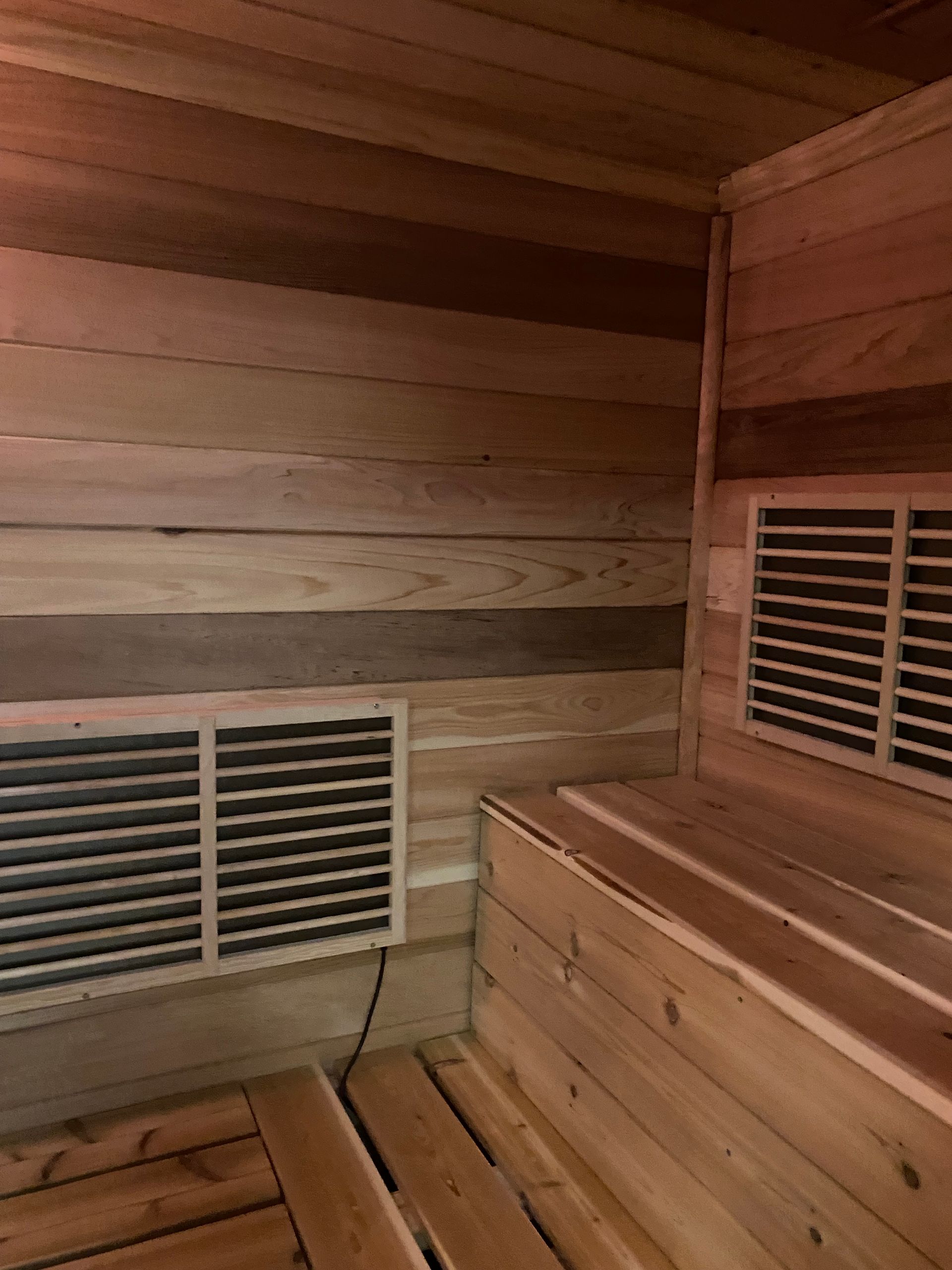 Wood-paneled sauna interior with two vents and wooden benches.