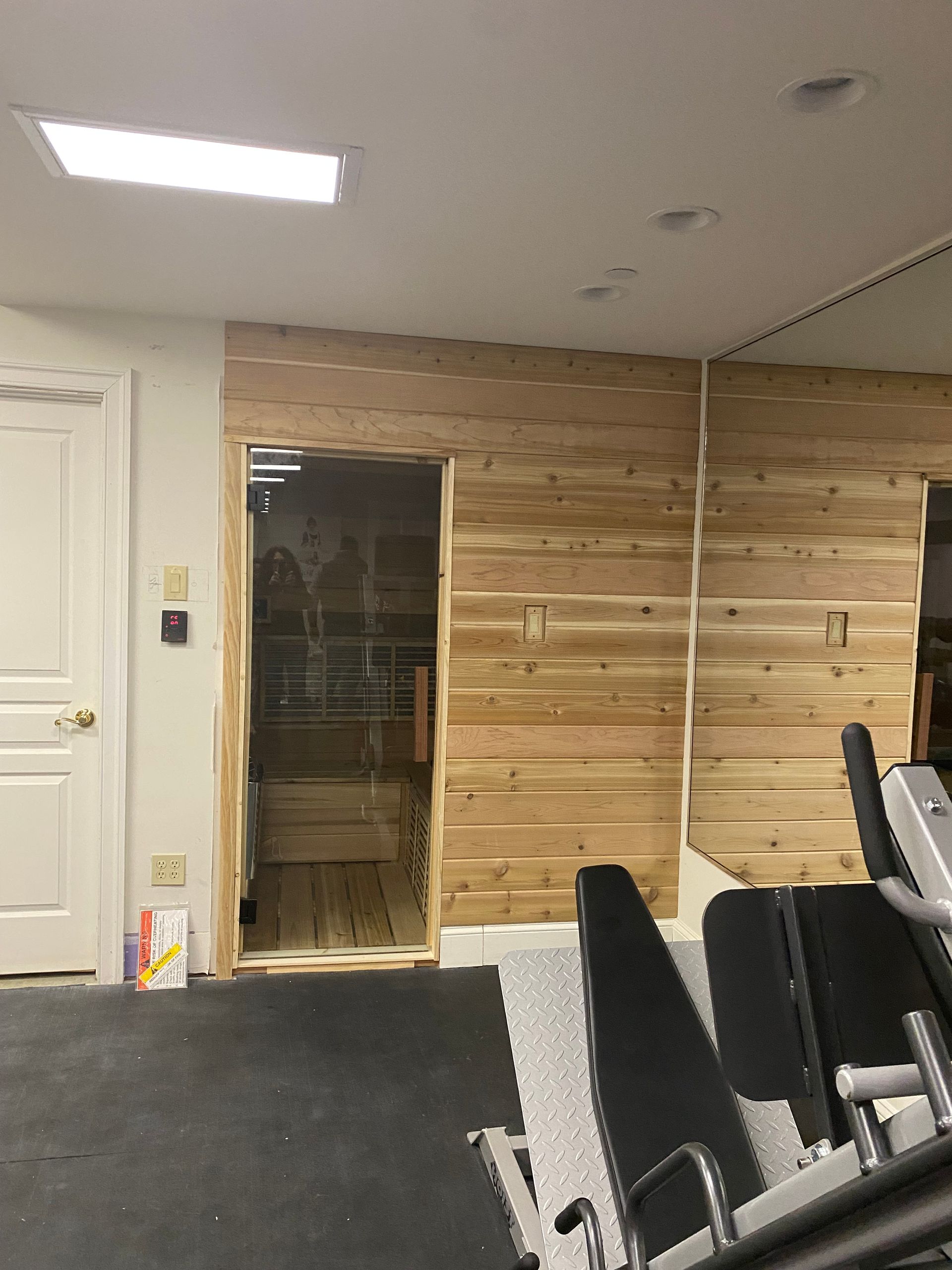 Wood-paneled room with open doorway, carpeted floor, and stacked chairs on the right.