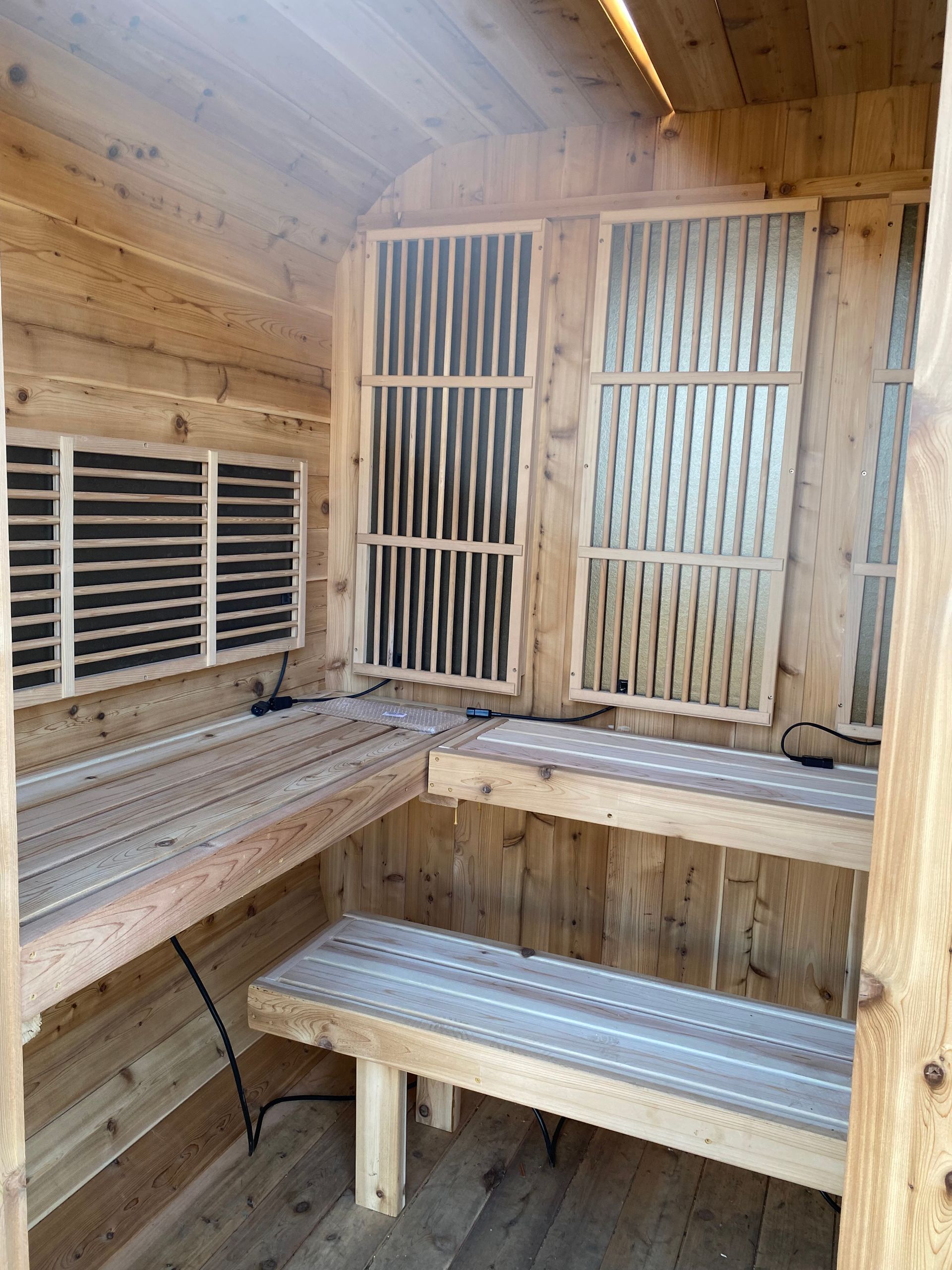 Outdoor custom infrared sauna with wooden benches and slatted ventilation grilles on the walls and door