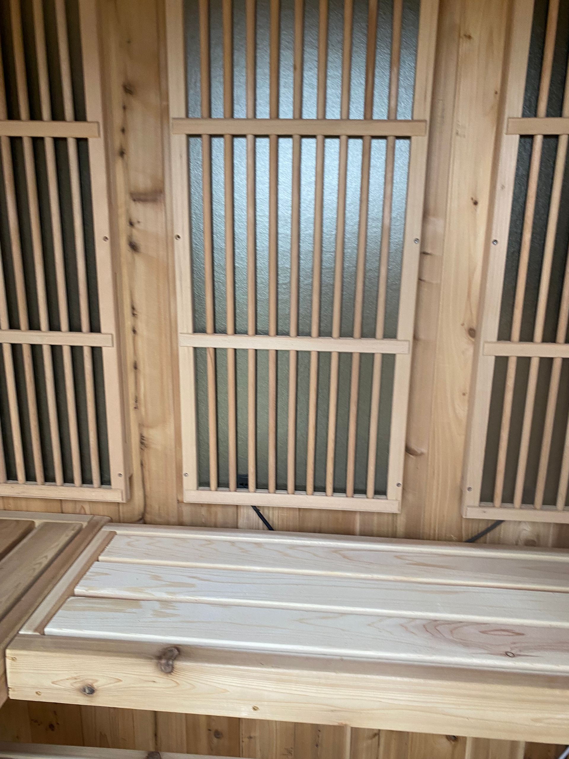 Wooden sauna bench and slatted wall with frosted glass window panels.