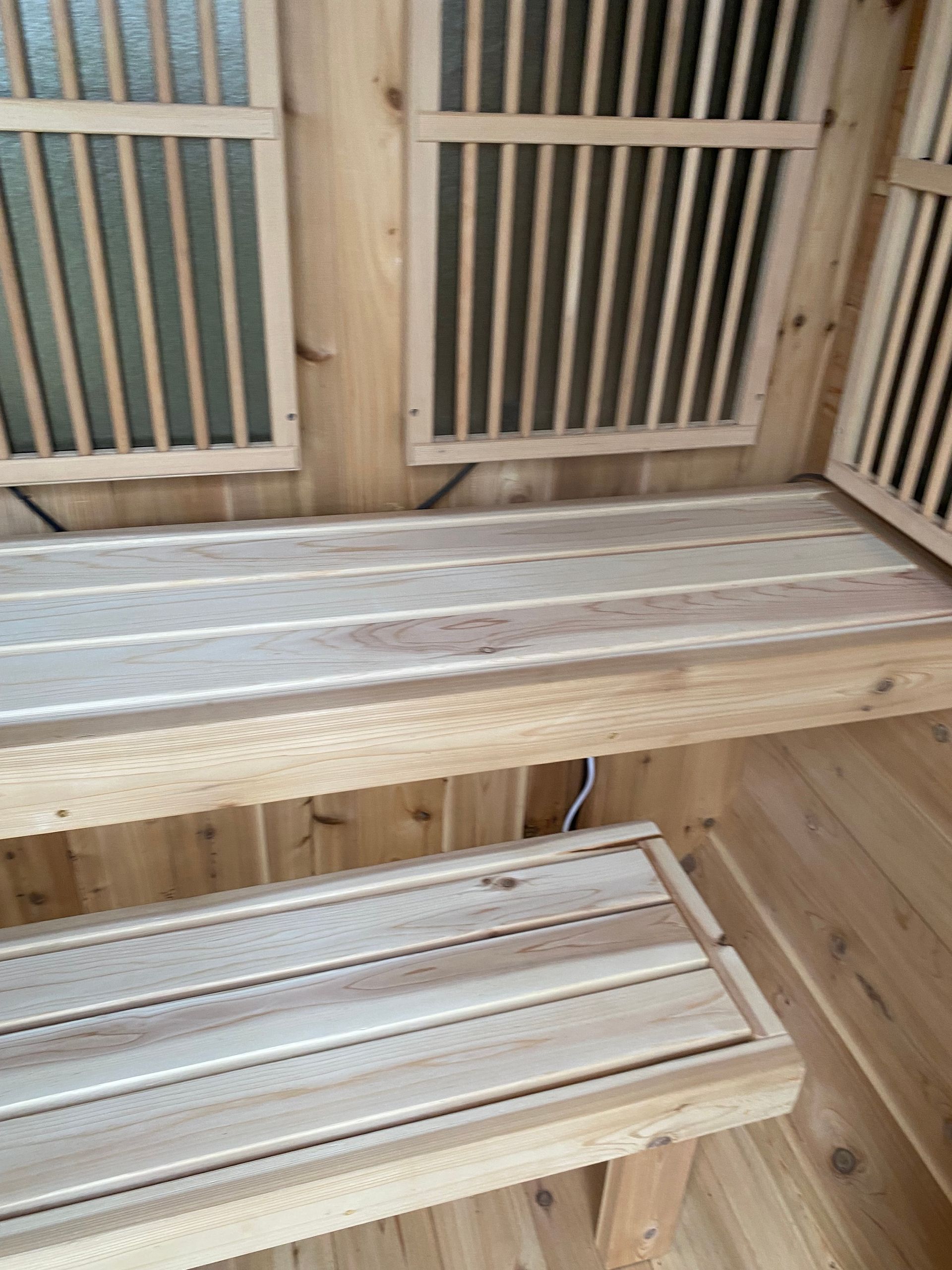 Wooden sauna interior with two slatted benches and a heater panel in the corner