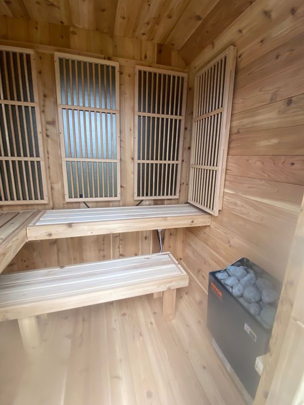 Wood-paneled sauna with wooden benches and slatted backrests, plus a heater in the corner.