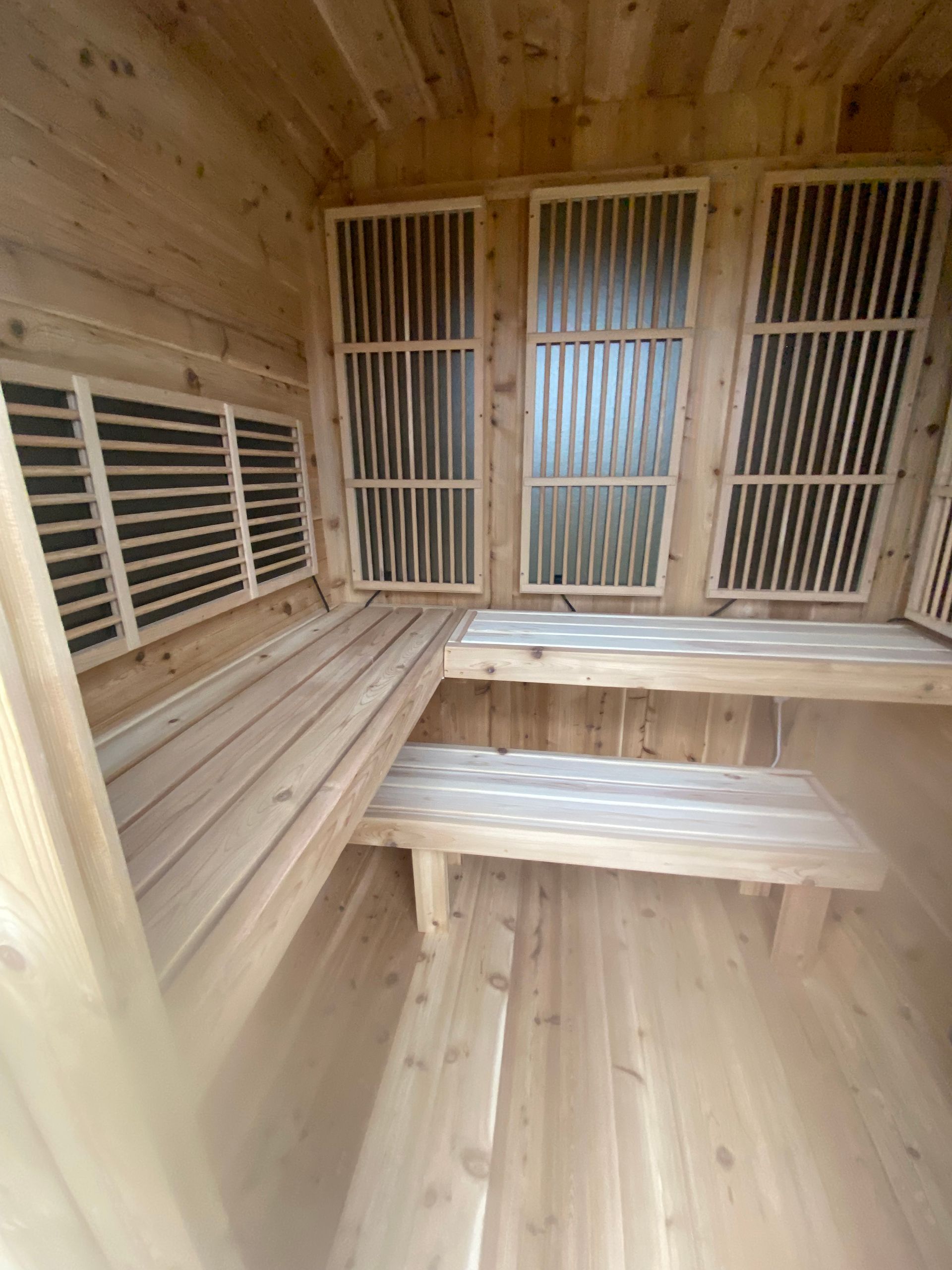 Wood-paneled sauna interior with slatted benches and wooden heater guards