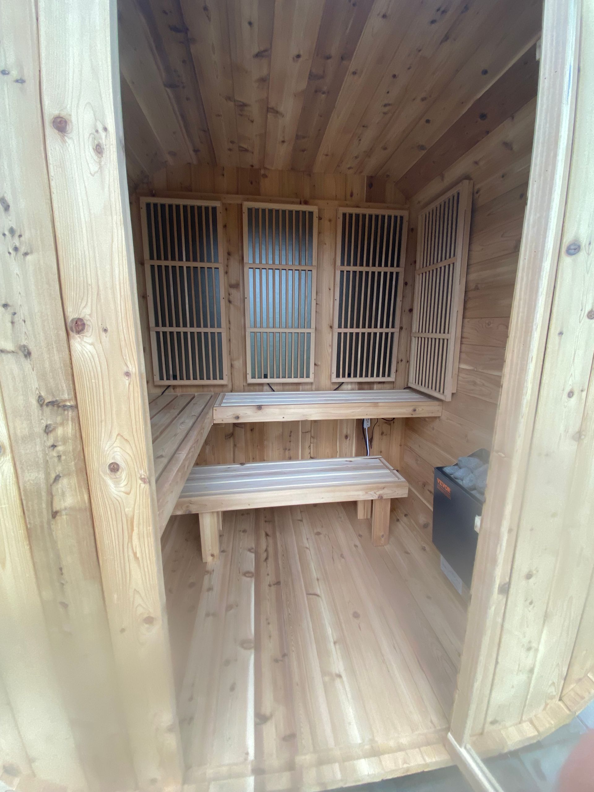 Wooden sauna interior with benches and slatted vents on the back wall
