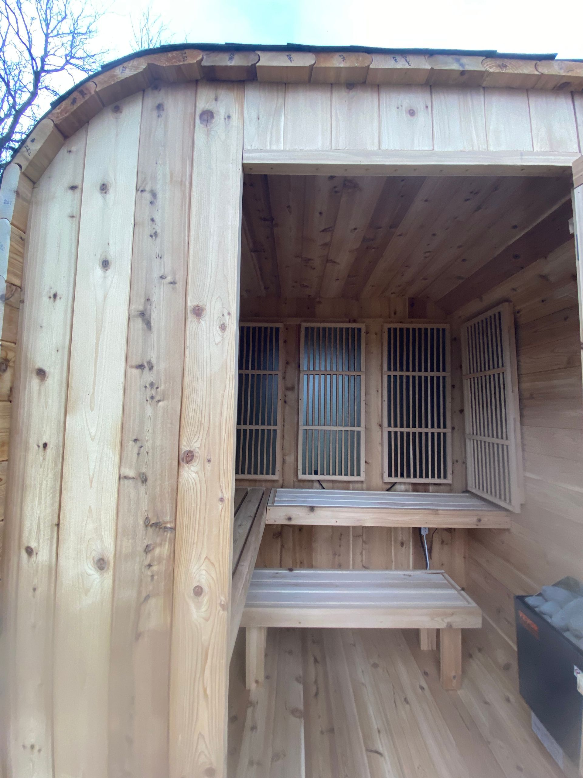 Wooden sauna interior with bench seating and a heater in the corner