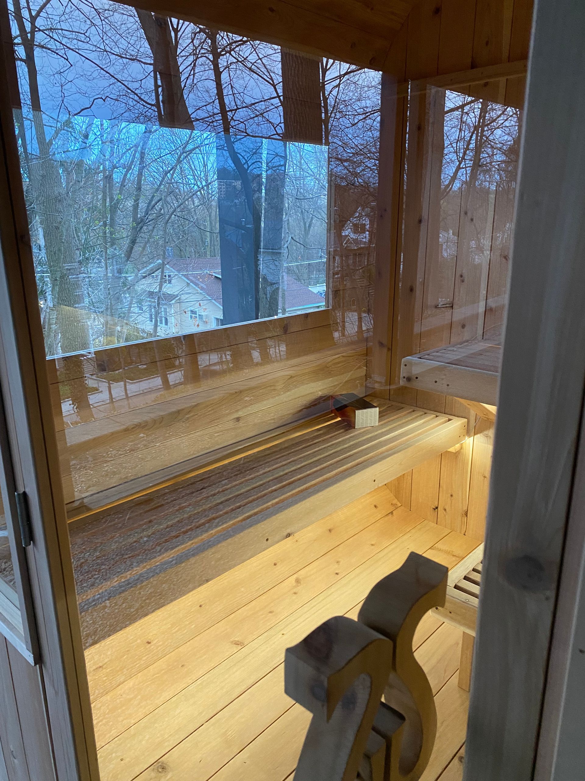 Looking into a custom outdoor sauna with glass built in New York by Uforia, under a porch