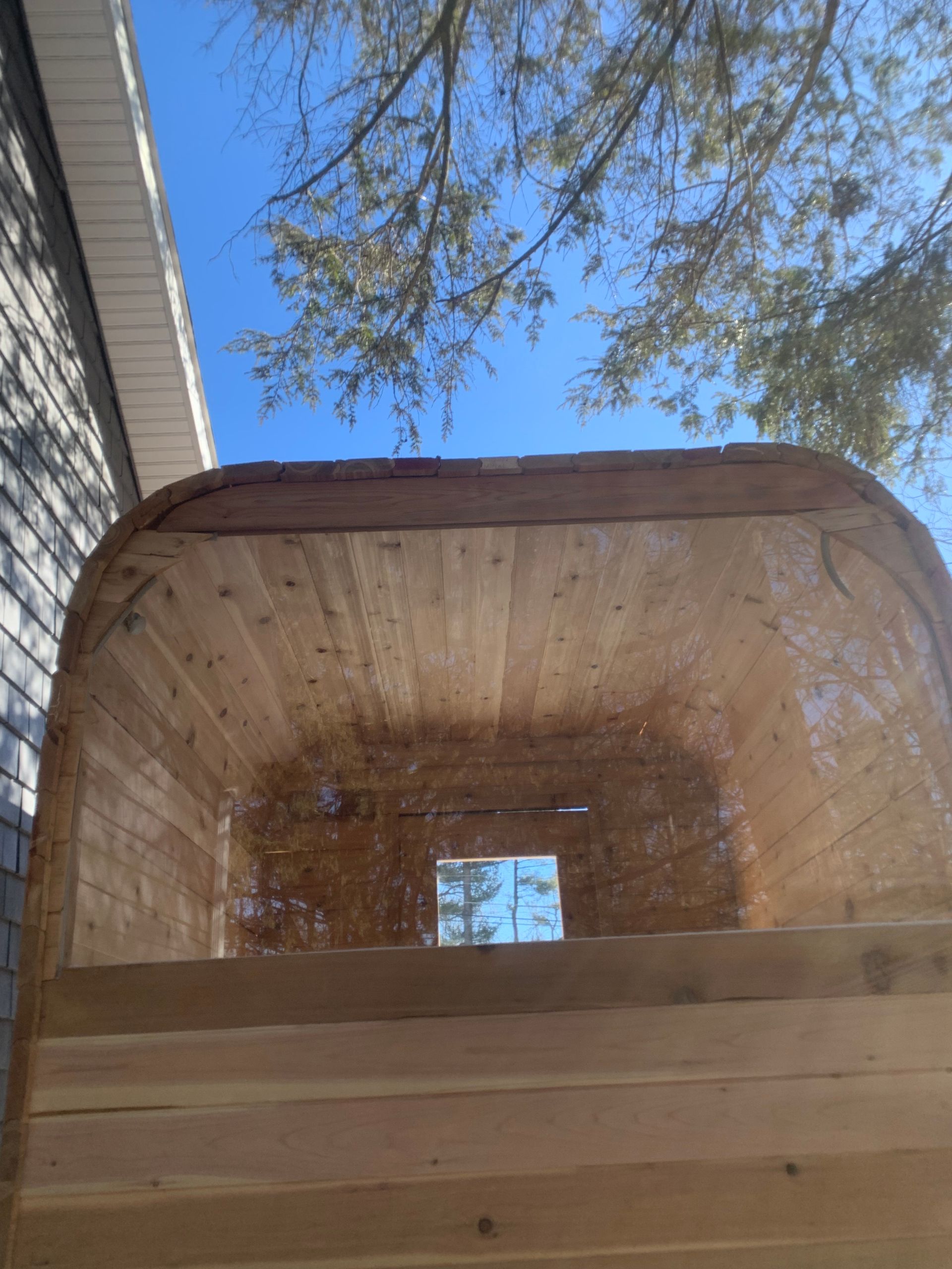 Wooden bucket or crate viewed from inside, with blue sky and tree branches overhead