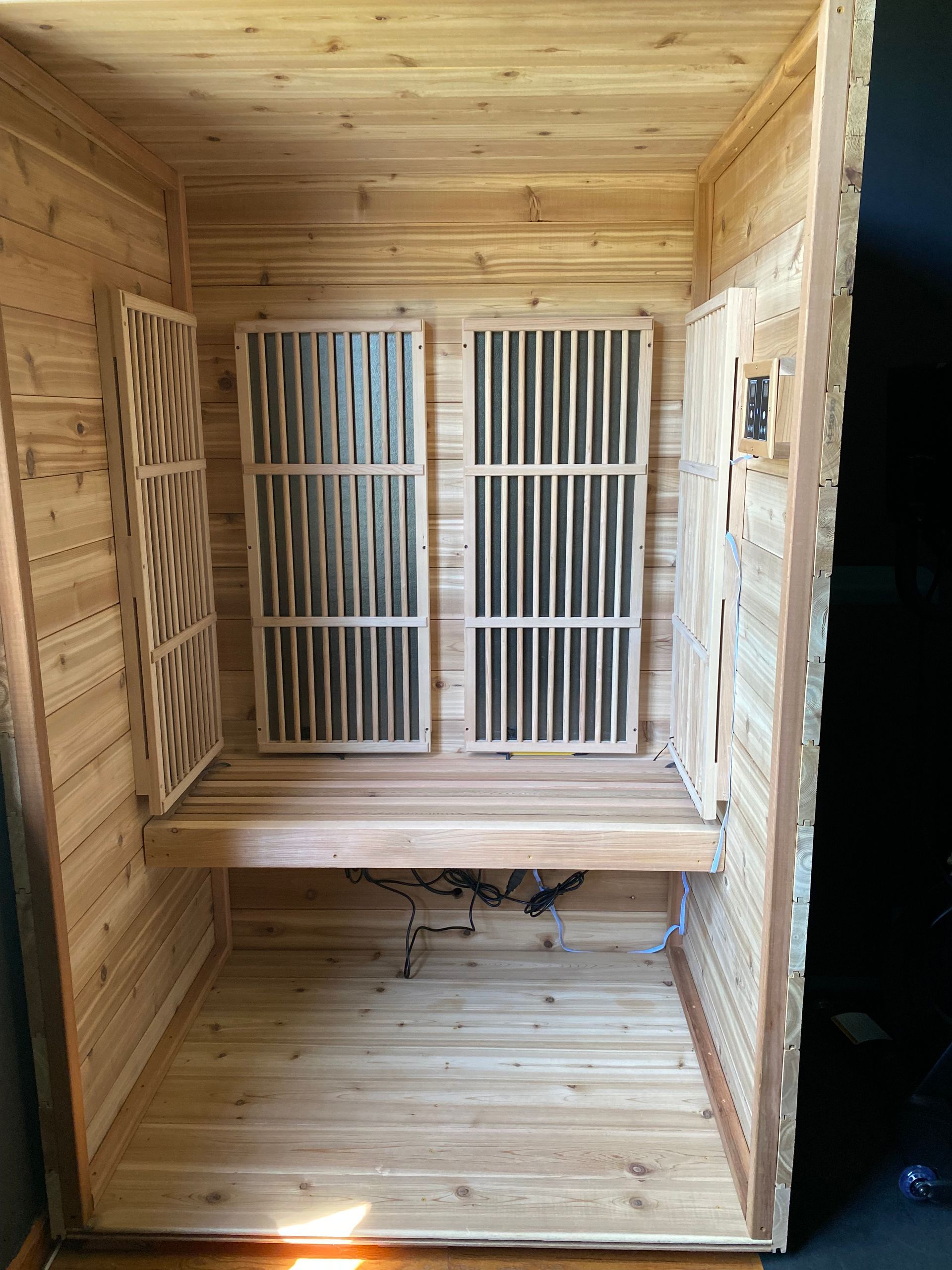 Wooden enclosure interior with slatted doors and a small bench-like shelf inside