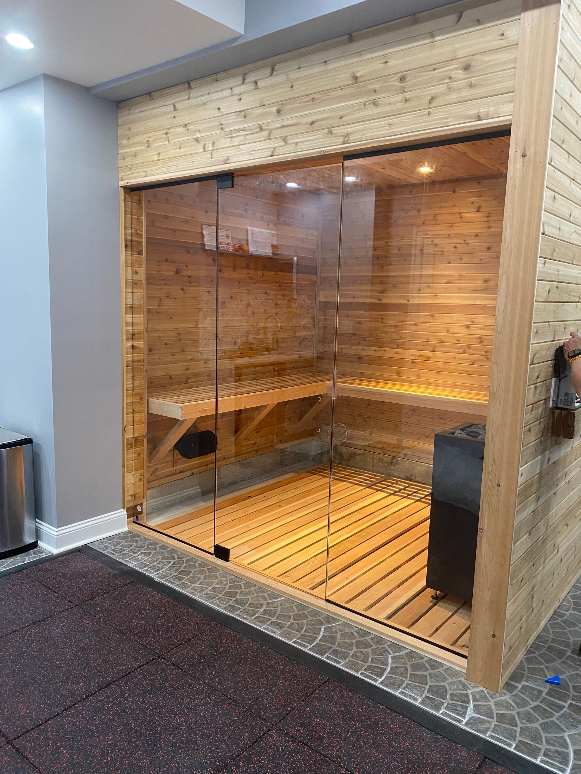 Wood-paneled sauna with glass front, benches, and warm interior lighting in a spa room