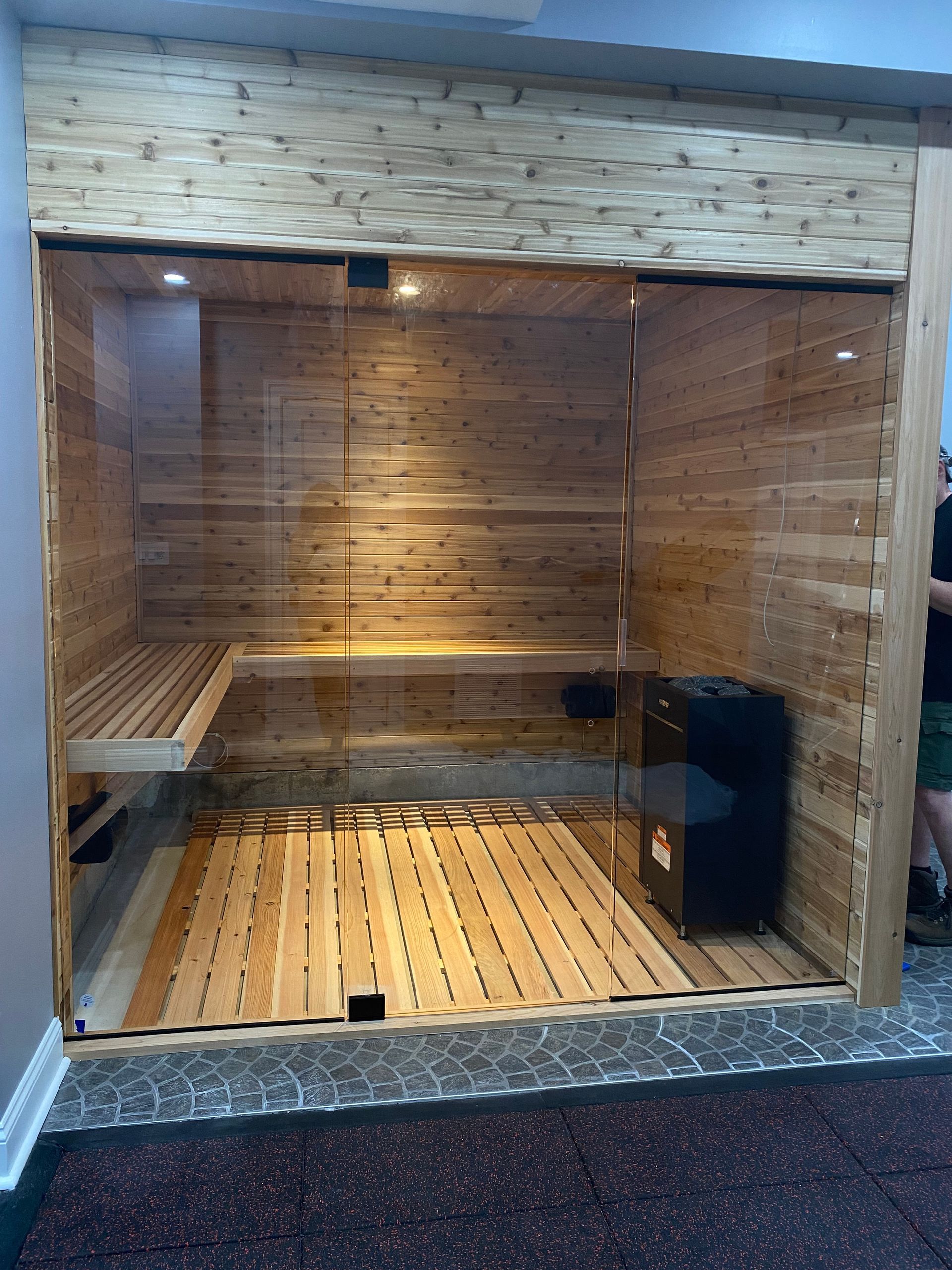 Empty wooden sauna with benches and glass front in a tiled room
